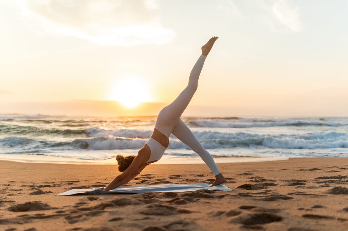 Young woman doing yoga on beach at sunset